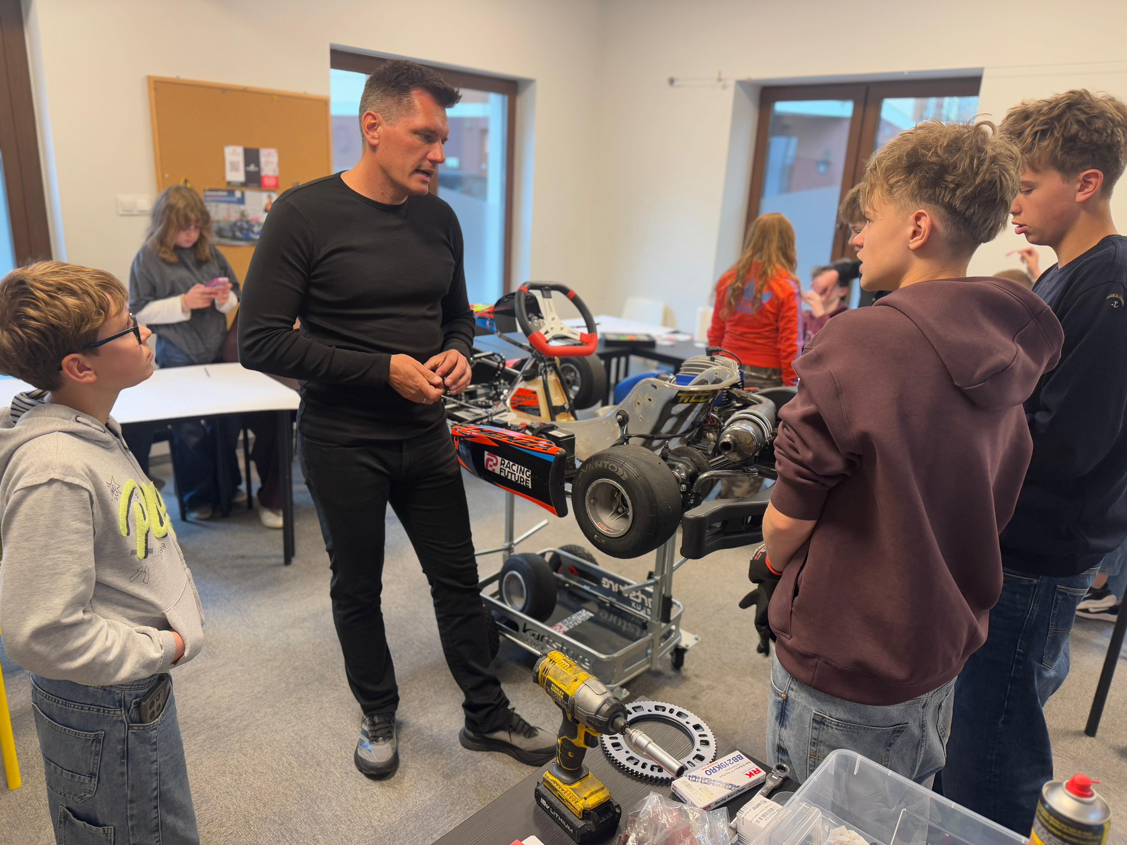 Marcin Budkowski and young learners gathered around a racing kart